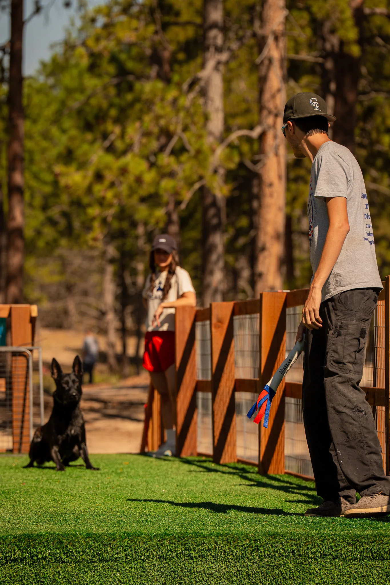 Handler facing a seated black dog on the pool dock.